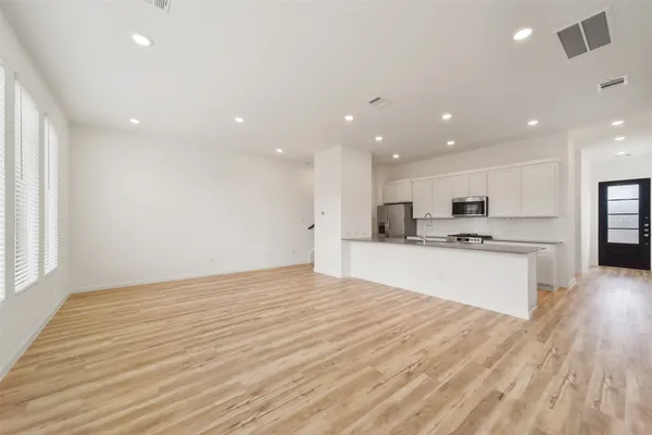 a large white kitchen with kitchen island a sink wooden floor and a refrigerator