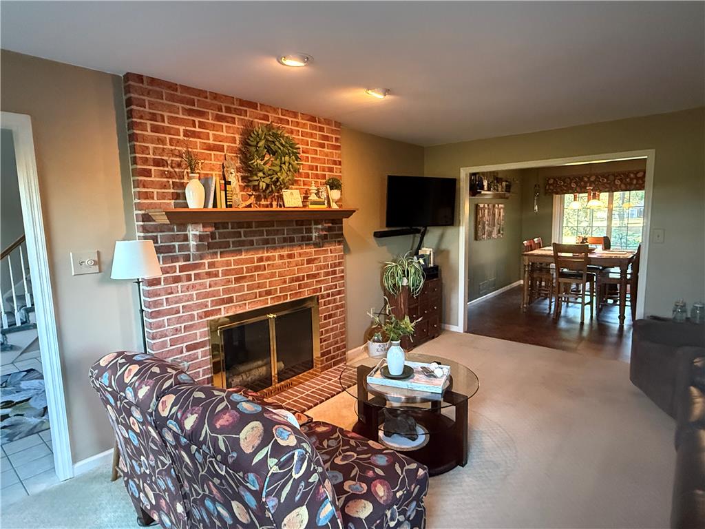 5616 Snowdrift Road Orefield, PA 18069 - Photo 11 of 36 A cozy living space features a warm brick fireplace with a mantel, flowing into a bright dining area.