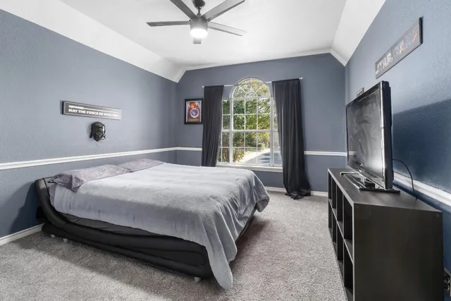 a bedroom with a bed and a flat tv screen on dresser