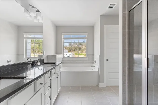 a bathroom with a granite countertop tub sink and mirror
