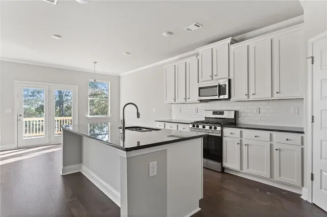 a kitchen with stainless steel appliances granite countertop white cabinets a sink and a stove