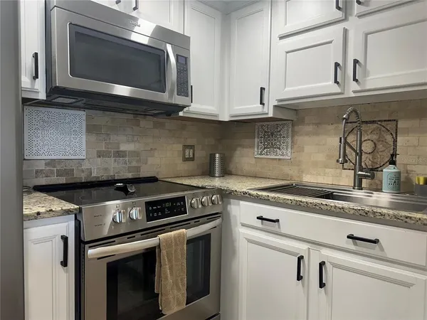 a kitchen with granite countertop white cabinets stainless steel appliances and a sink