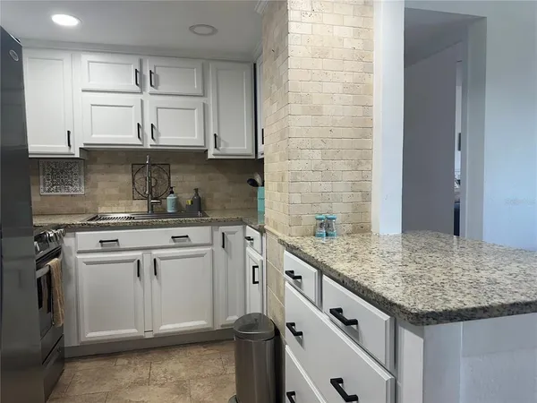 a kitchen with granite countertop white cabinets and white appliances