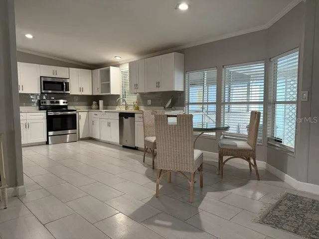 a living room with furniture a kitchen view and a flat screen tv