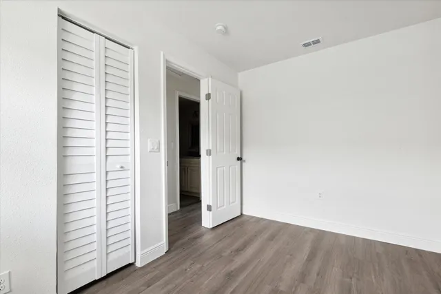 an empty room with wooden floor and closet