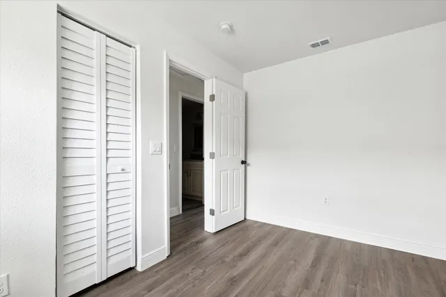 an empty room with wooden floor and closet