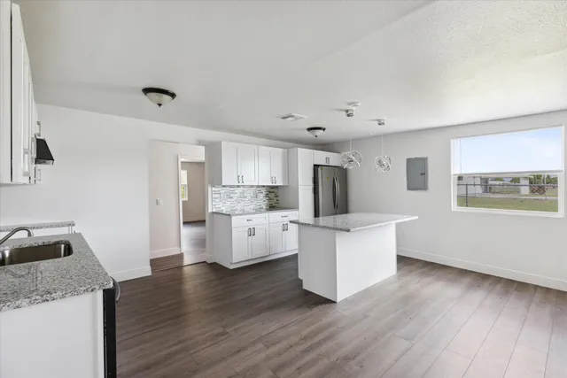 a kitchen with stainless steel appliances a sink a stove a refrigerator cabinets and a wooden floor