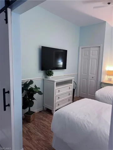 a bedroom with a bed and a flat tv screen on wall
