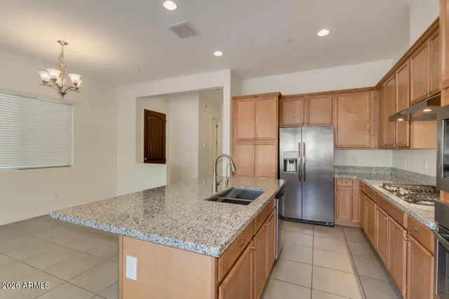a kitchen with granite countertop kitchen island stainless steel appliances a sink stove and refrigerator