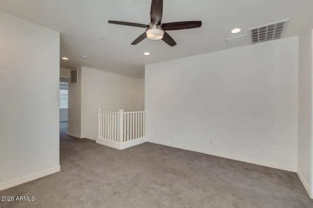 en empty room with stairs and a ceiling fan