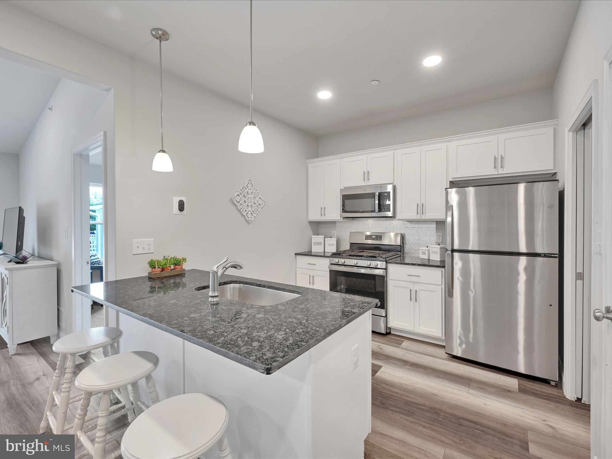 108 Staplehill Court Sinking Spring, PA 19608 - Photo 11 of 33 a kitchen with stainless steel appliances granite countertop a sink a stove a refrigerator a microwave oven with white cabinets and wooden floor