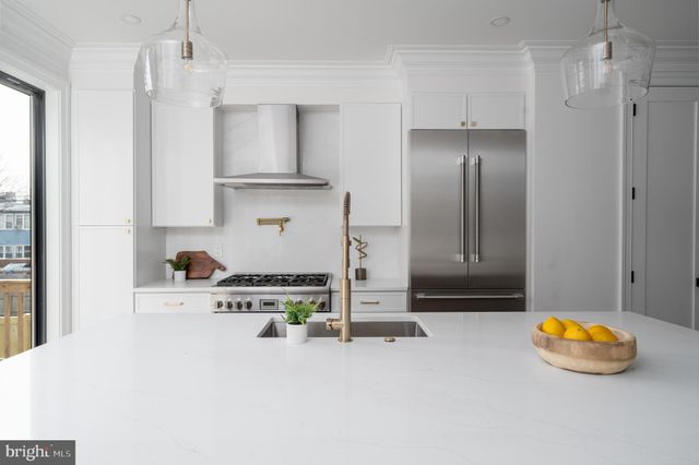 a kitchen with stainless steel appliances a refrigerator a sink a stove and a refrigerator with wooden floor