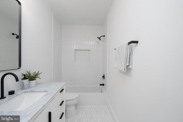 a bathroom with a granite countertop sink a toilet and shower