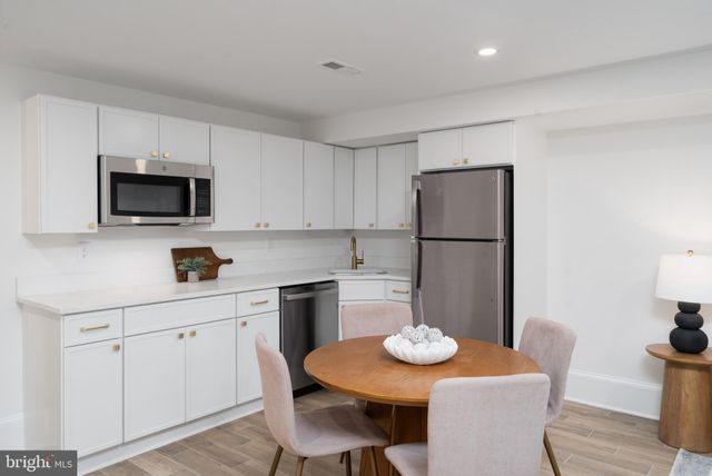a kitchen with stainless steel appliances granite countertop a dining table and chairs