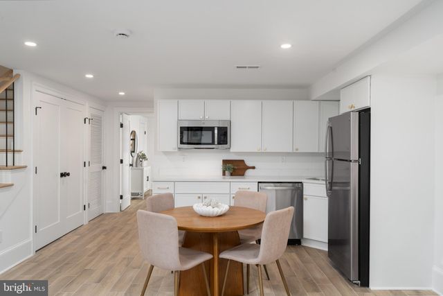 a kitchen with stainless steel appliances a refrigerator a stove a sink dishwasher and white cabinets with wooden floor