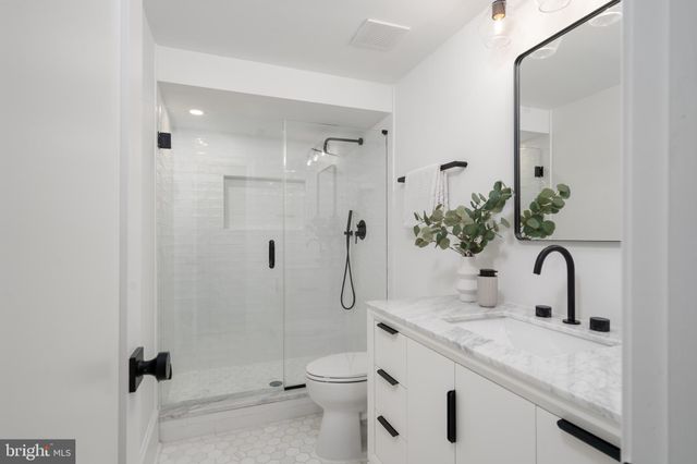 a bathroom with a granite countertop sink a toilet and shower