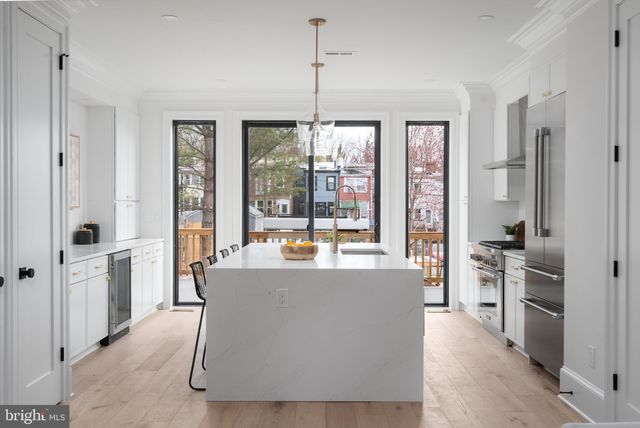 a living room with furniture a large window and stainless steel appliances