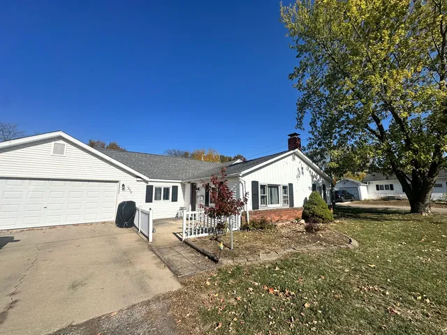a view of a white house next to a yard with large trees