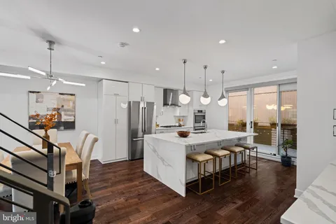 a kitchen with a stove a sink a window and chairs