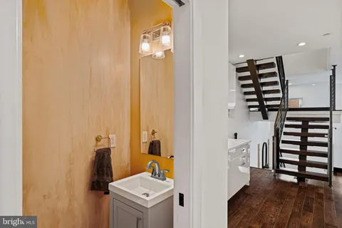 a kitchen with stainless steel appliances a stove a sink a dining table and chairs with wooden floor