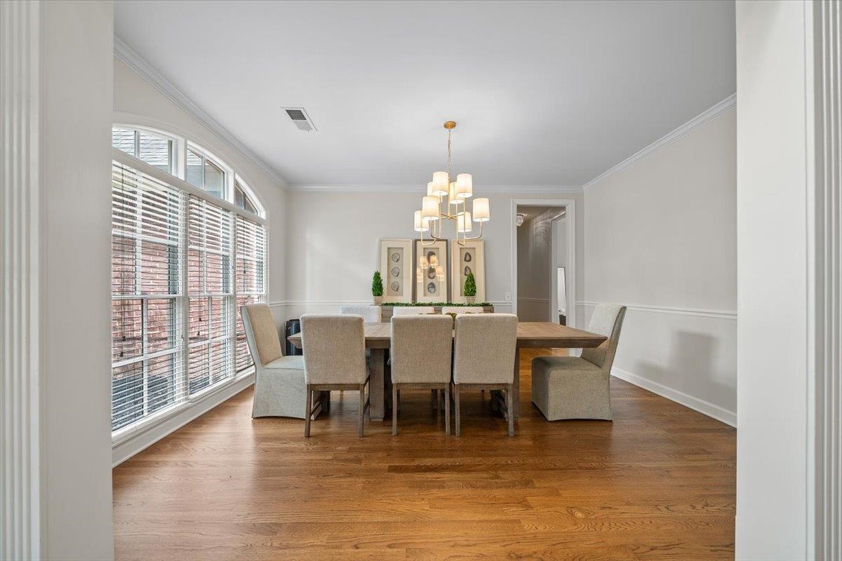 1876 Liles Lane Collierville, TN 38017 - Photo 15 of 36 Dining area featuring wood-finish flooring, a large arched window with horizontal blinds, wainscoting, crown molding, and a multi-arm chandelier
