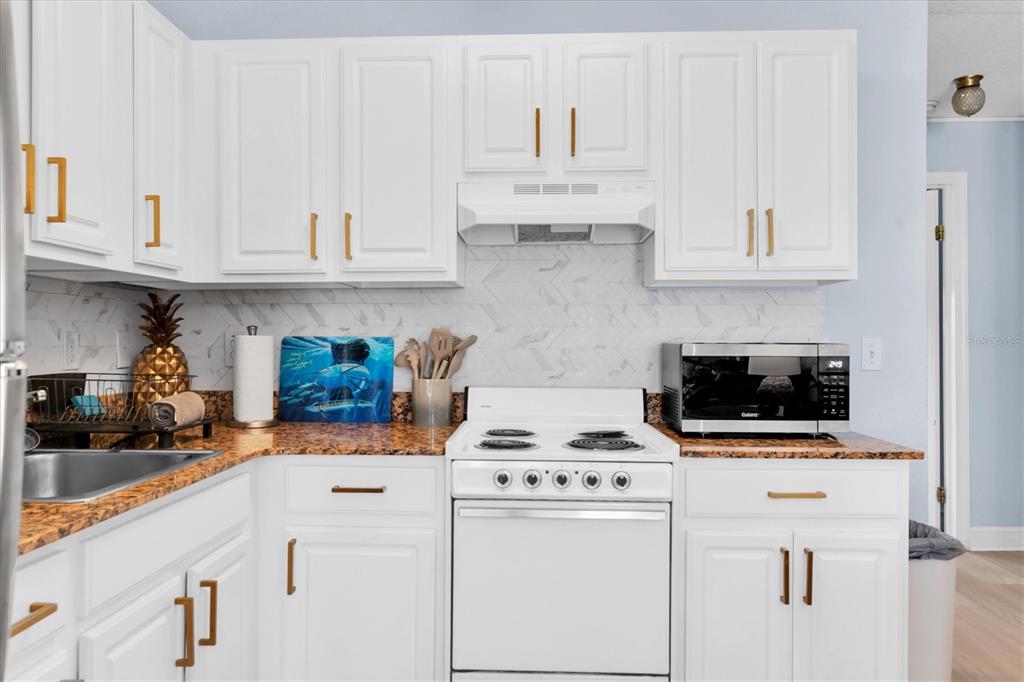 16333 Gulf Boulevard, Unit 217 St. Petersburg, FL 33708 - Photo 11 of 30 a kitchen with white cabinets and white appliances