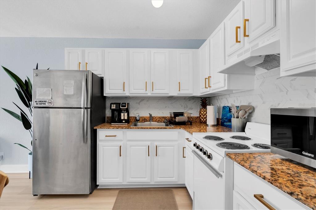16333 Gulf Boulevard, Unit 217 St. Petersburg, FL 33708 - Photo 12 of 30 a kitchen with stainless steel appliances granite countertop a refrigerator stove a sink and dishwasher