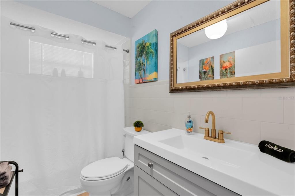 16333 Gulf Boulevard, Unit 217 St. Petersburg, FL 33708 - Photo 16 of 30 a bathroom with a sink a mirror a toilet and a window