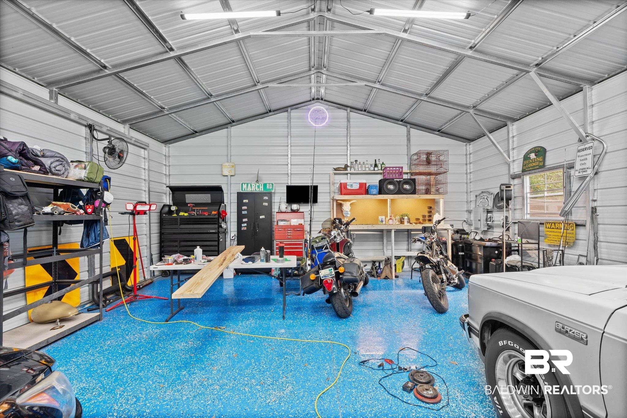 4213 Shan Drive East Mobile, AL 36693 - Photo 26 of 35 Spacious garage featuring a durable blue epoxy floor, extensive overhead lighting, and corrugated metal walls