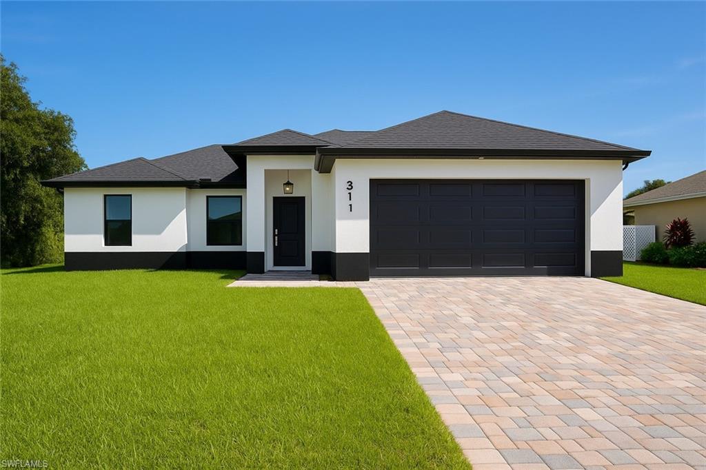 311 Ranier Avenue Lehigh Acres, FL 33974 - Photo 3 of 32 Prairie-style house with a front lawn, decorative driveway, stucco siding, and an attached garage