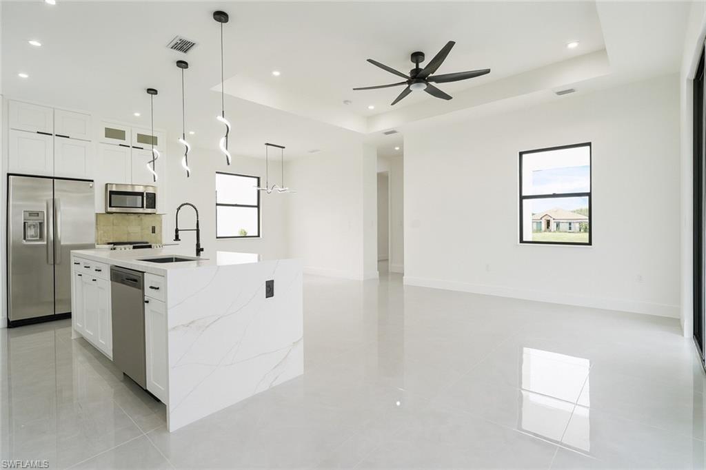 311 Ranier Avenue Lehigh Acres, FL 33974 - Photo 7 of 32 Kitchen featuring white cabinetry, appliances with stainless steel finishes, a raised ceiling, light stone countertops, and recessed lighting