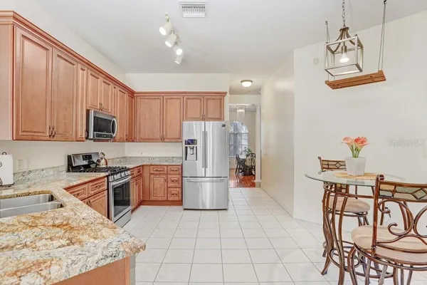 a kitchen with stainless steel appliances granite countertop a refrigerator a stove top oven a sink dishwasher and a stove with wooden floor