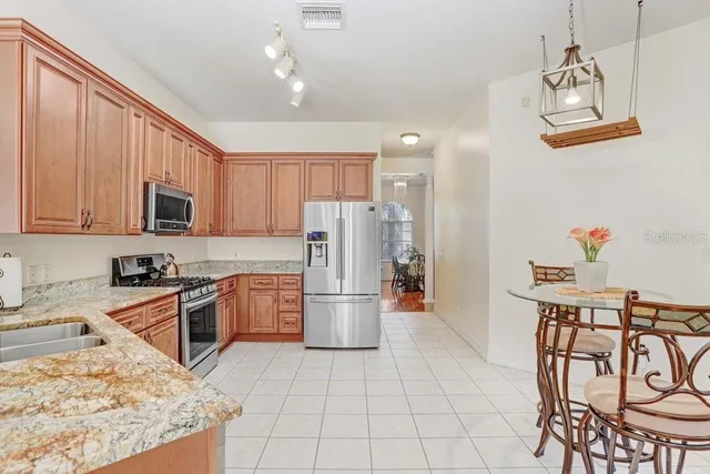 a kitchen with stainless steel appliances granite countertop a refrigerator a stove top oven a sink dishwasher and a stove with wooden floor