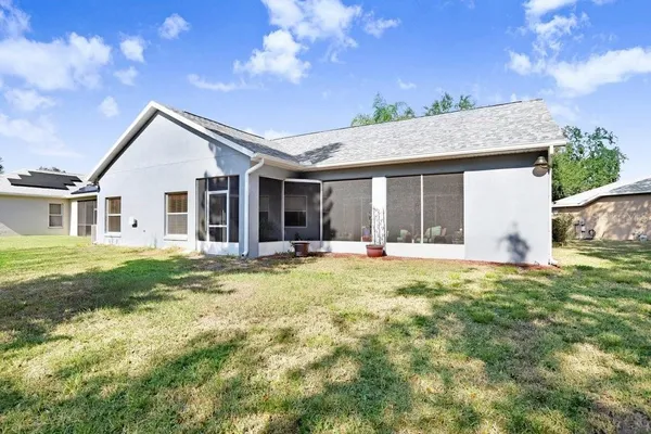 a backyard of a house with table and chairs and potted plants