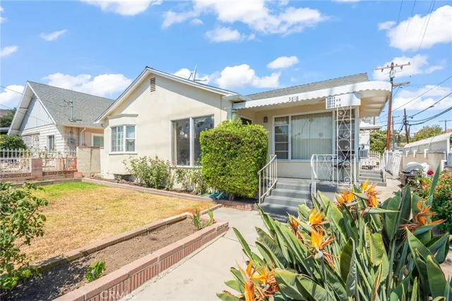 a view of a house with potted plants and a large tree