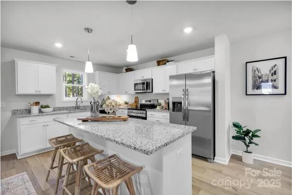 a kitchen with granite countertop kitchen island stainless steel appliances a refrigerator a sink a stove a table and chairs