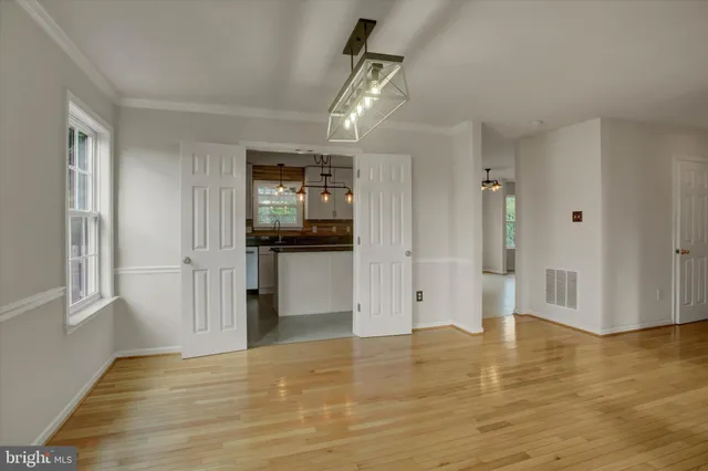 a kitchen with stainless steel appliances kitchen island granite countertop a stove top oven a sink a refrigerator and white cabinets with wooden floor