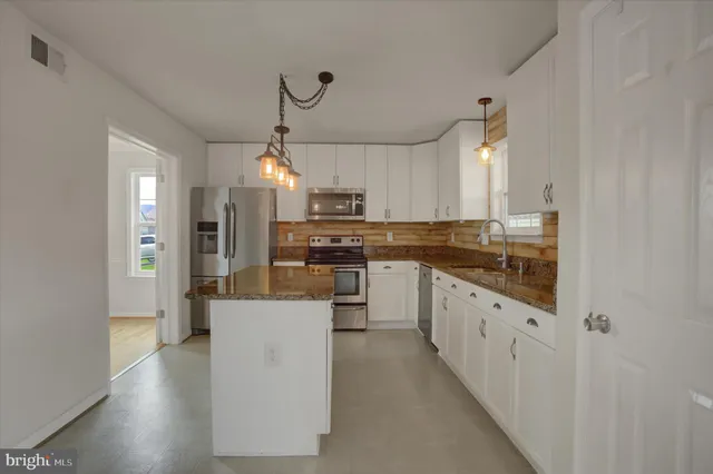 a kitchen with granite countertop a sink a counter top space and cabinets