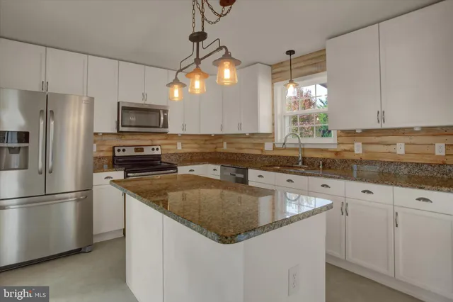 a view of an empty room with a chandelier fan and a fireplace
