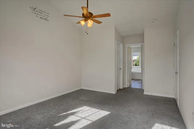 a view of an empty room and chandelier fan