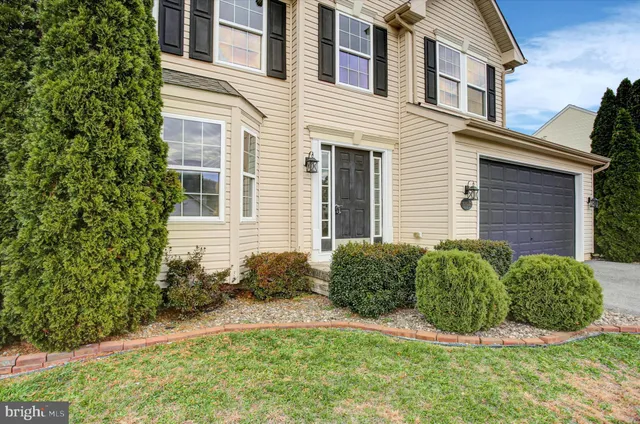 a view of a house with brick walls plants and large tree