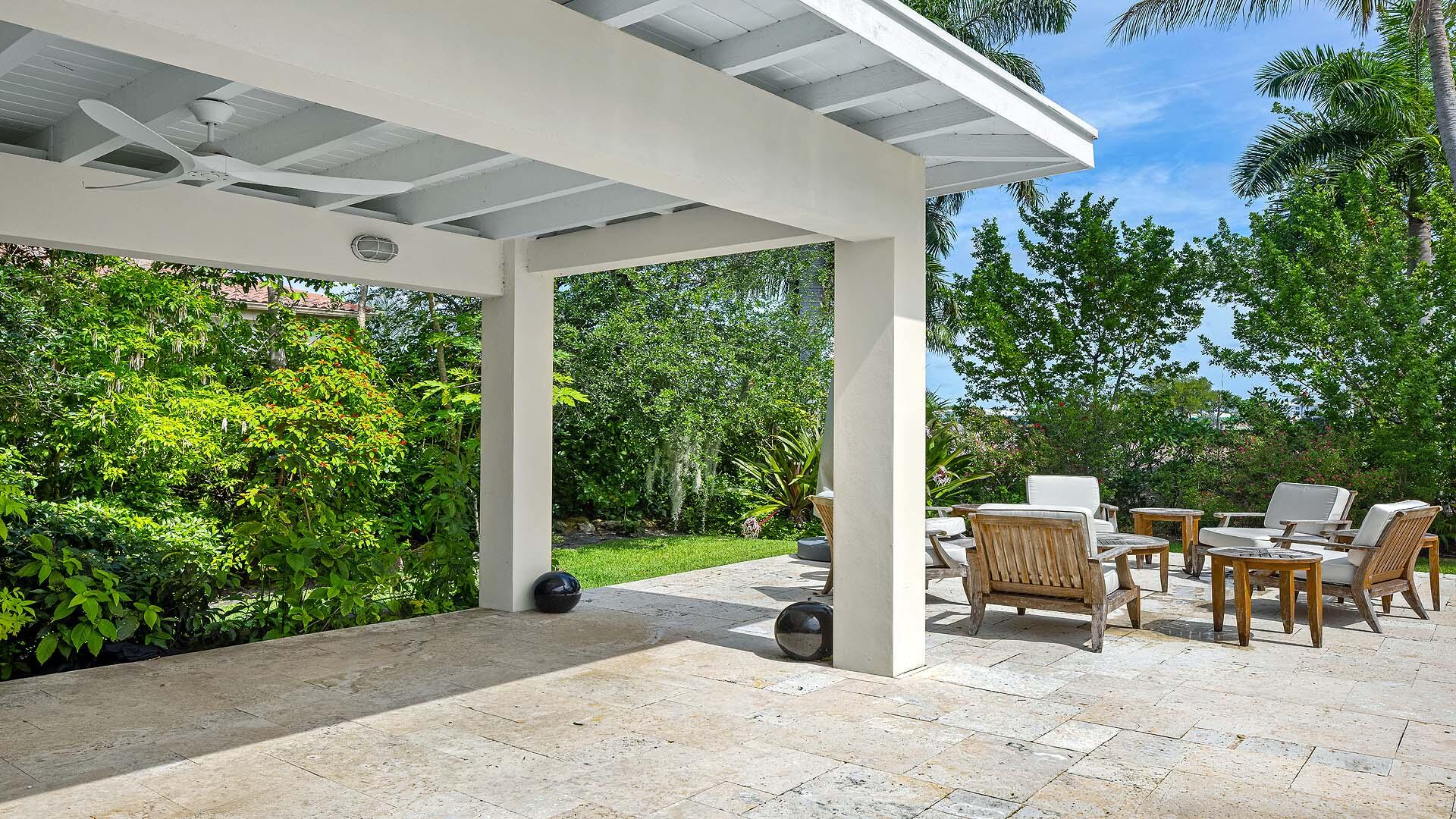335 Old School Road Gulf Stream, FL 33483 - Photo 28 of 29 a view of a patio with table and chairs potted plants with wooden fence