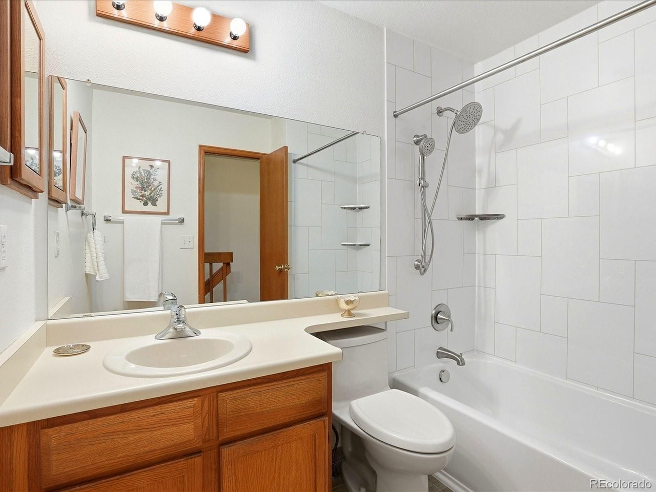 1818 South Quebec Way, Unit 2 Denver, CO 80231 - Photo 13 of 16 a bathroom with a sink toilet a mirror and shower