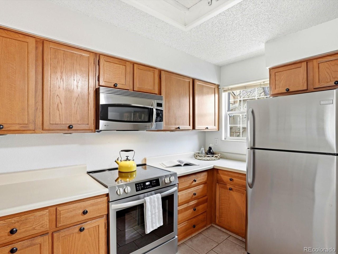1818 South Quebec Way, Unit 2 Denver, CO 80231 - Photo 6 of 16 a kitchen with stainless steel appliances granite countertop a refrigerator stove a sink dishwasher and microwave with cabinets