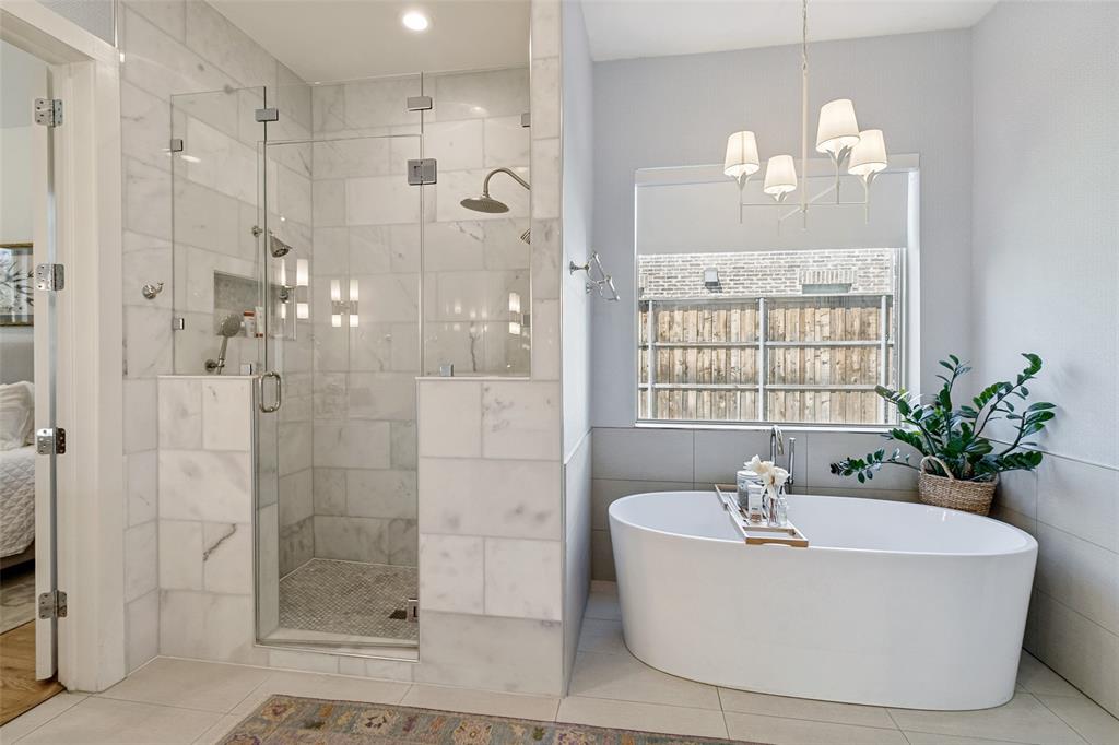 7533 Garonne Street Dallas, TX 75231 - Photo 13 of 32 a white bath tub sitting in a bathroom with a chandelier
