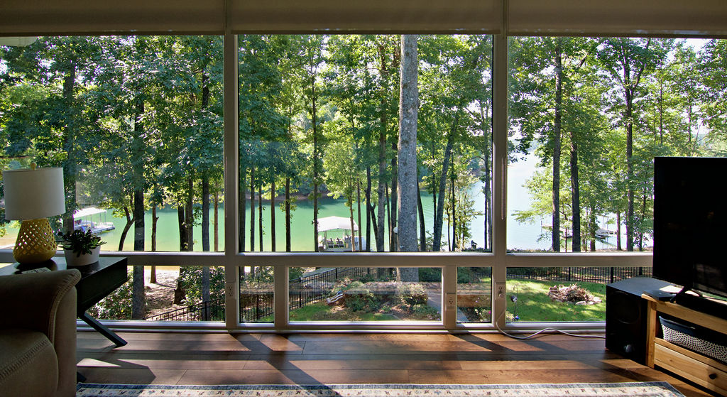 11001 Lake Ridge Lane Seneca, SC 29672 - Photo 20 of 50 Expansive floor-to-ceiling windows frame serene waterfront views past towering mature trees.