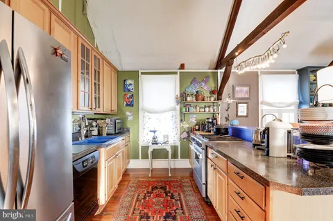 a kitchen with stainless steel appliances granite countertop a refrigerator a stove and a sink with wooden floor