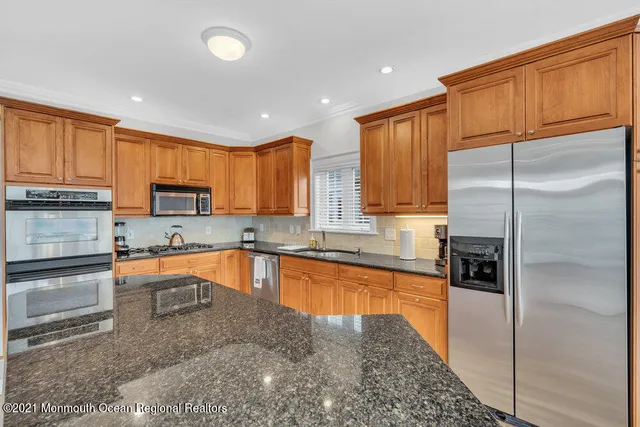 a kitchen with stainless steel appliances granite countertop a refrigerator a sink a stove top oven and a refrigerator