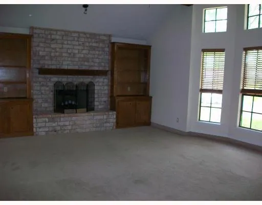 an empty room with windows and fireplace