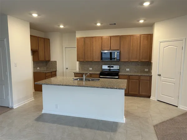 a kitchen with stainless steel appliances granite countertop a stove a sink and a refrigerator with white cabinets